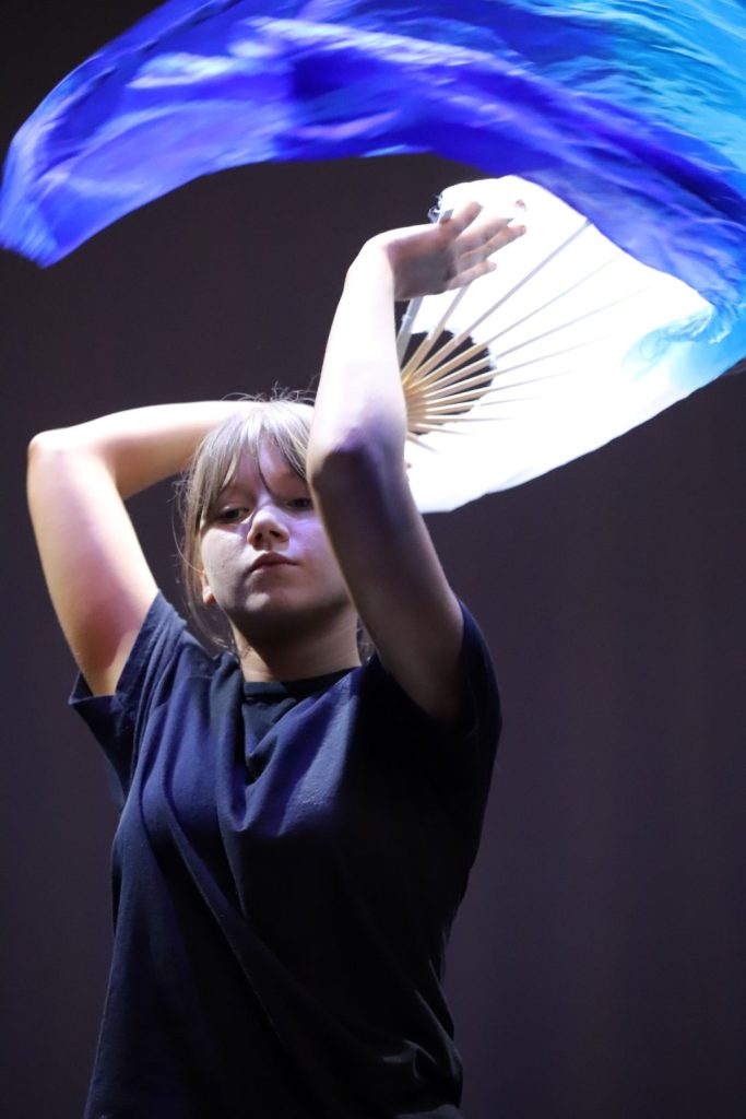 Young woman dancing with long piece of fabric